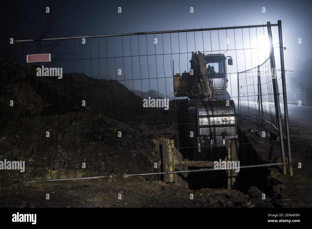 Blauer Bagger arbeitet nachts auf der Straße Stockfoto