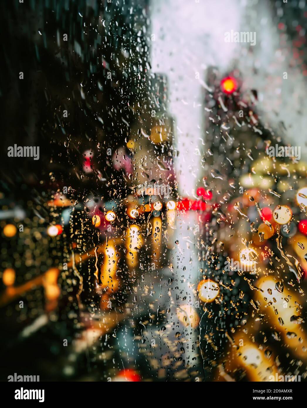 Verschwommener Straßenhintergrund in New York City mit Wassertropfen, Lichtern und Autos bei Regen am Abend Stockfoto
