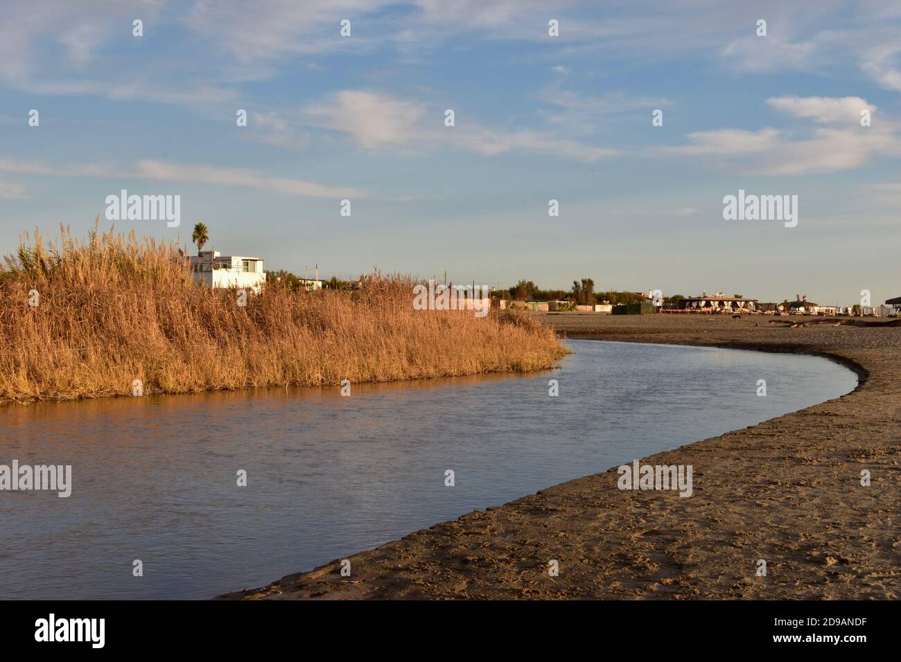 Kleiner Fluss Entspannen Sie sich vor der Flussmündung ins Tyrrenische Meer. Ruhe und Gelassenheit. Landschaftlich reizvolle Farben. Weiße Hütte, die aus einem dichten Schilf hervortritt. Stockfoto