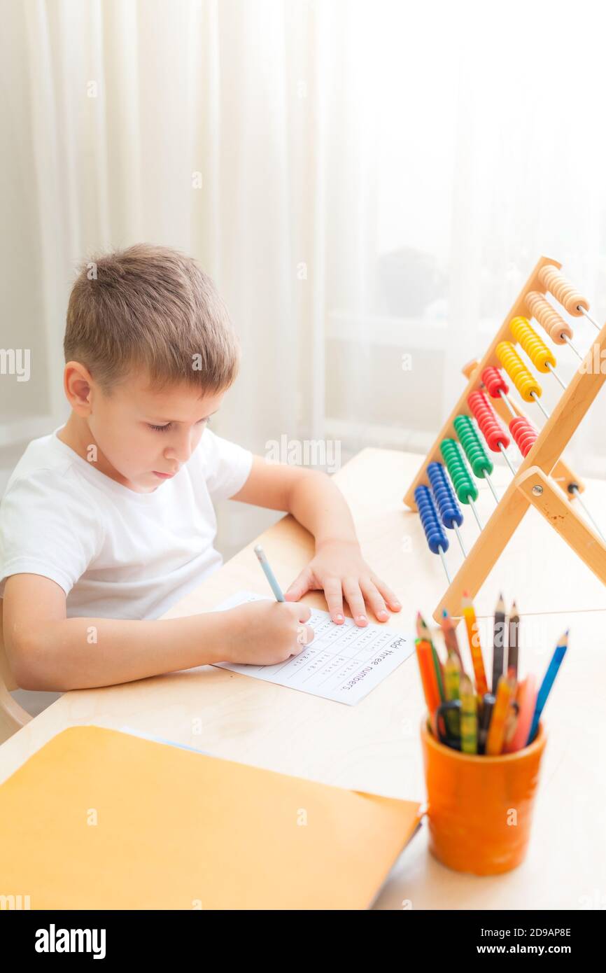 Seitenansicht der Kinder, die mathematische Übungen lösen. 7 Jahre altes Kind, das Mathematik-Unterricht macht, sitzt am Schreibtisch in seinem Zimmer. Stockfoto
