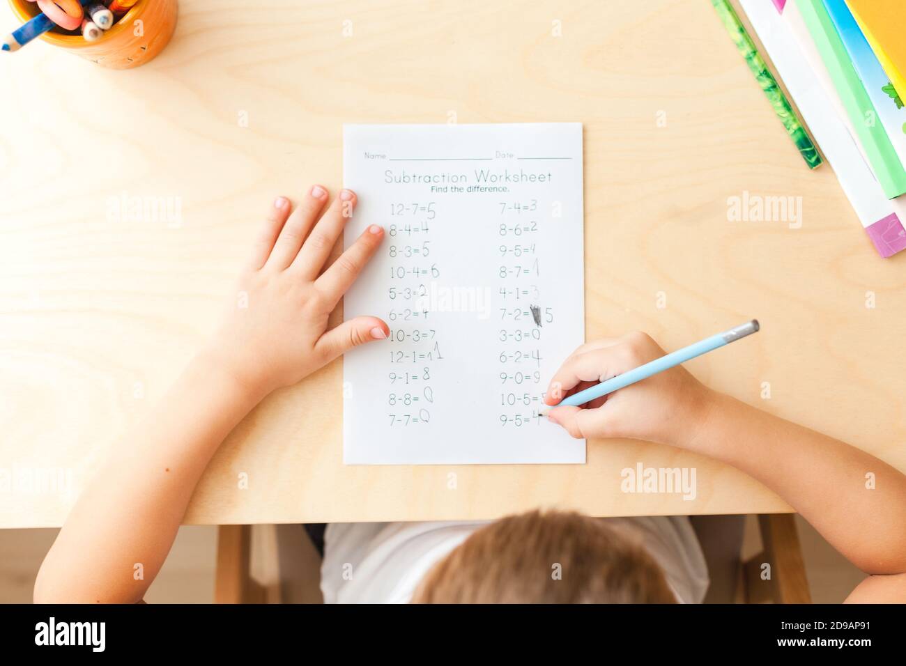 Draufsicht auf Kinderhände mit Bleistiften. Mathematische Übungen lösen. 7 Jahre altes Kind, das Mathematik-Unterricht macht, sitzt am Schreibtisch in seinem Zimmer. Stockfoto