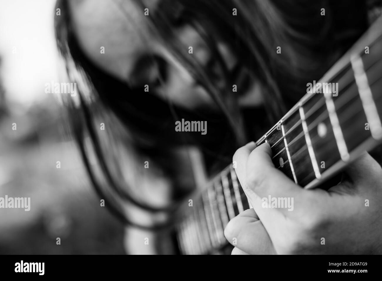 Finger auf den Saiten, Mädchen spielt akustische Gitarre. Schwarzweiß-Fotografie. Stockfoto