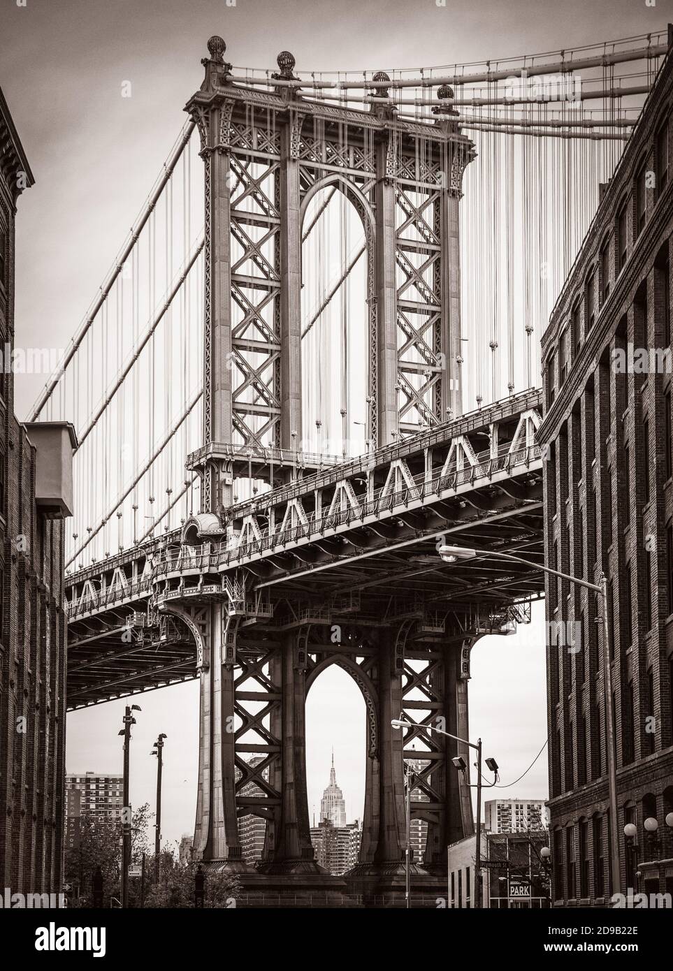 Manhattan Bridge und Empire State Building von Brooklyn aus gesehen. Alte Fotostilisierung, Filmkörnung hinzugefügt. Sepia getönte Stockfoto