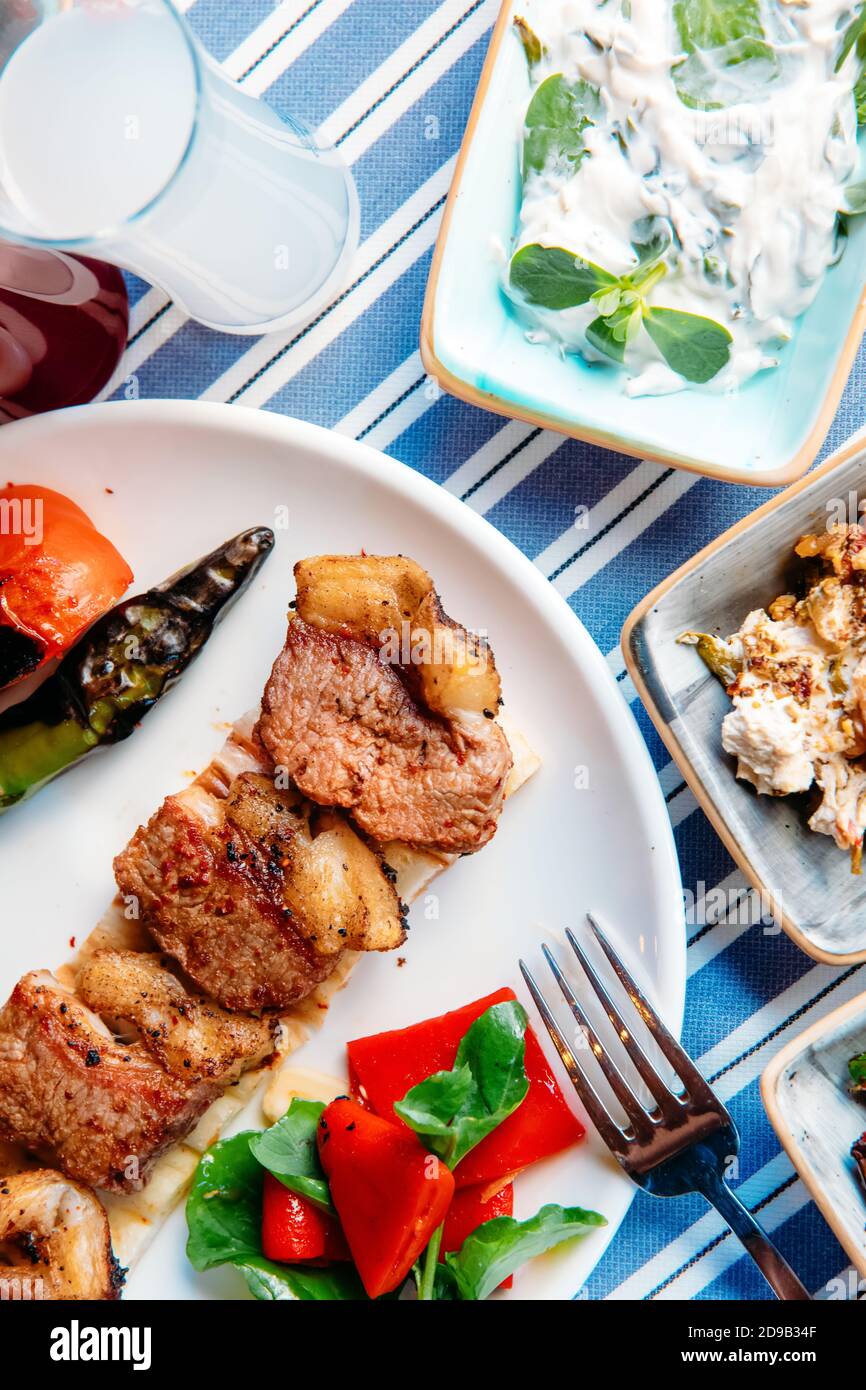 Gegrilltes Fleisch, Meeresfrüchte, Meze, Kräuter, Fisch, Raki, Ouzo, Vorspeisen und Salate im griechischen oder türkischen Restaurant auf dem Tisch zum Abendessen oder Mittagessen am Strand Stockfoto