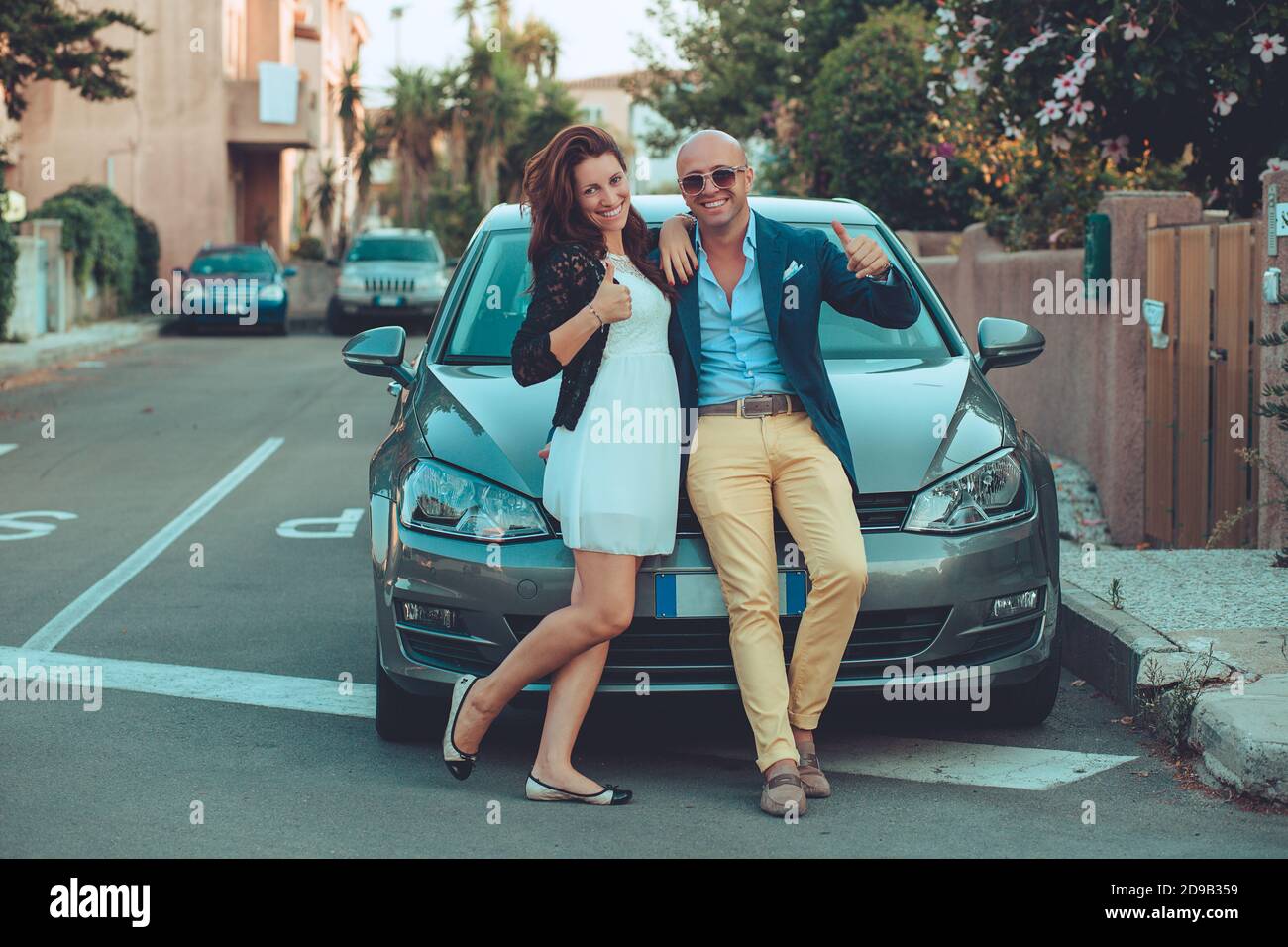 Glücklich Mann und Frau niedlich stilvolle Paar neben seinem Auto stehen und geben einen Daumen nach oben, weil sie wirklich wie es im Freien städtischen Straßenhintergrund. Stockfoto