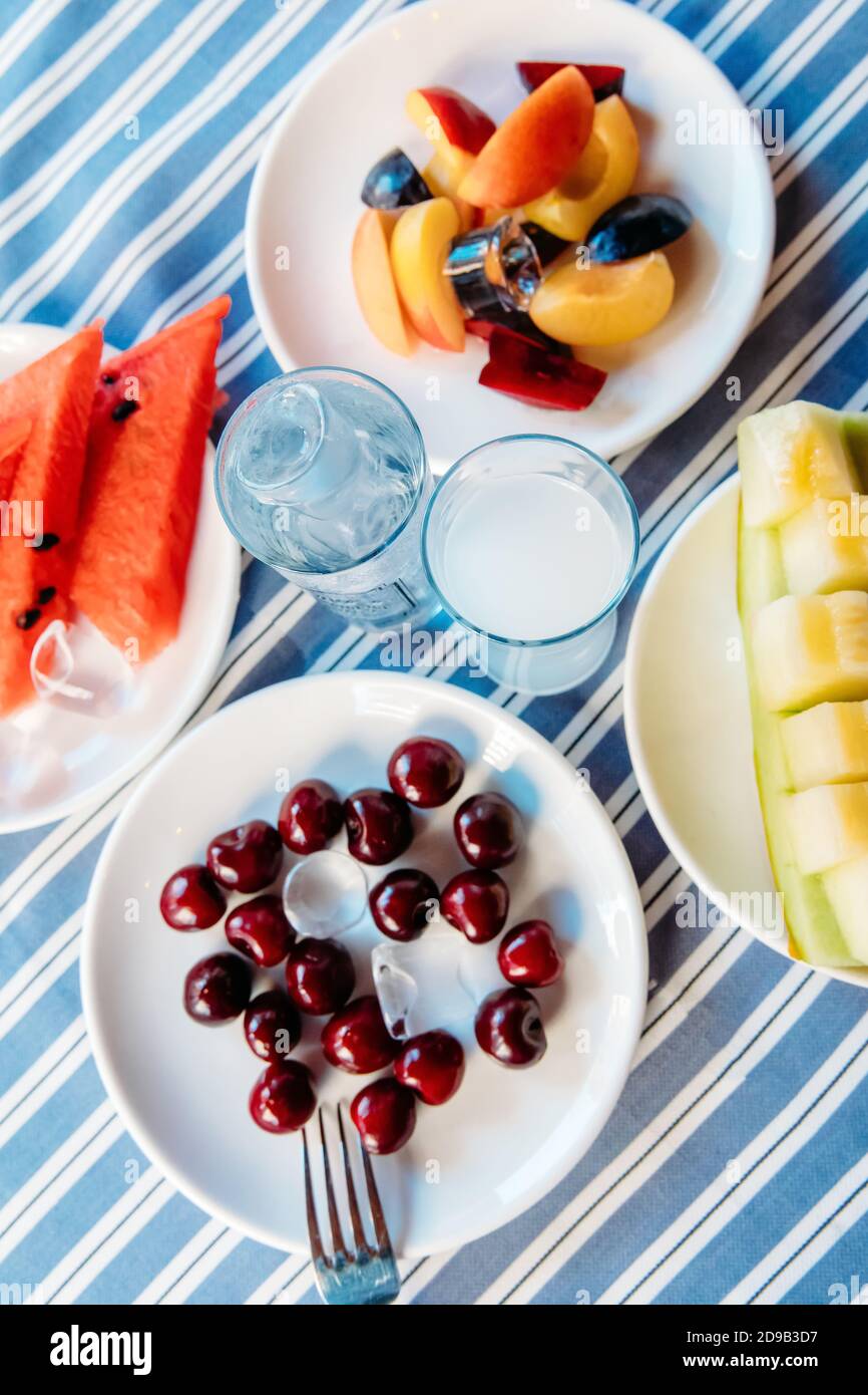 Griechischer Ouzo oder türkischer Raki mit Obstsalat und Vorspeisen Essen im griechischen oder türkischen Fischrestaurant zum Abendessen oder Mittagessen am Strand Stockfoto