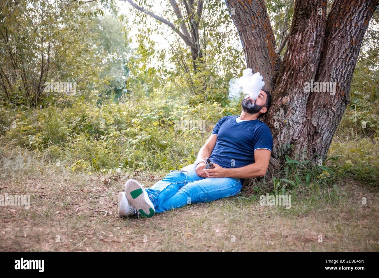 Selbstbewusster Mann dampft und gibt eine Wolke aus Dampf ab. Alternative zum Rauchen. Stockfoto