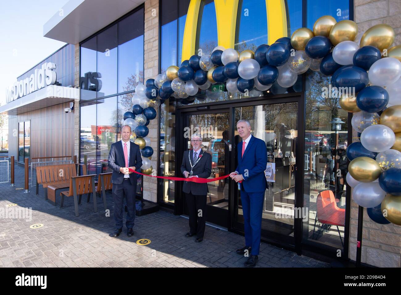 Der Bürgermeister von Oakham, David Romney (Mitte), schneidet ein Band, um offiziell ein neues McDonald's-Restaurant zu eröffnen, das am Stadtrand von Oakham liegt, da Rutland die letzte Grafschaft in England wird, die eine Zweigstelle des Fast-Food-Restaurants hat. Stockfoto