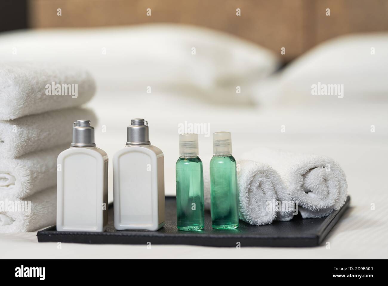 Nahaufnahme von wunderschön gefalteten weißen Handtüchern und Toilettenartikeln auf dem Bett im Hotelzimmer. Speicherplatz kopieren. Servicekonzept des Hotels Stockfoto