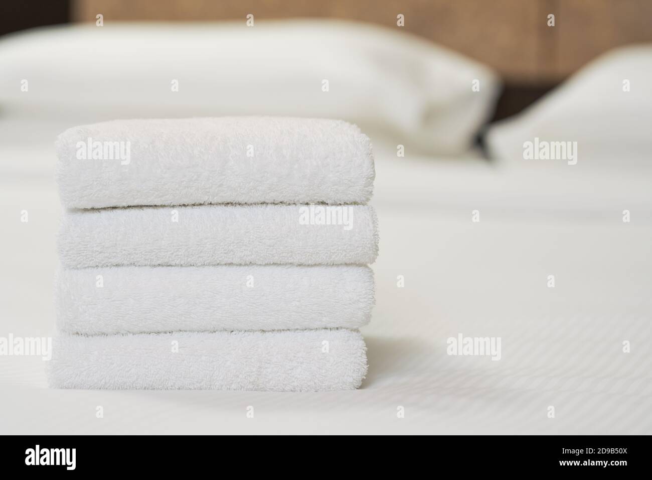 Nahaufnahme von vier weißen Handtüchern auf dem Bett im Hotelzimmer für den Kunden. Speicherplatz kopieren. Servicekonzept des Hotels Stockfoto