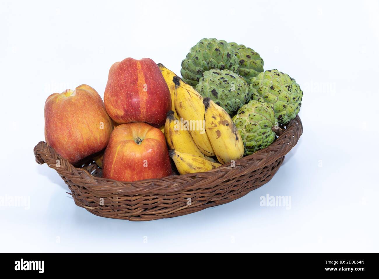 Frische Äpfel, Bananen und Puddingäpfel auf einem Holzkorb Stockfoto
