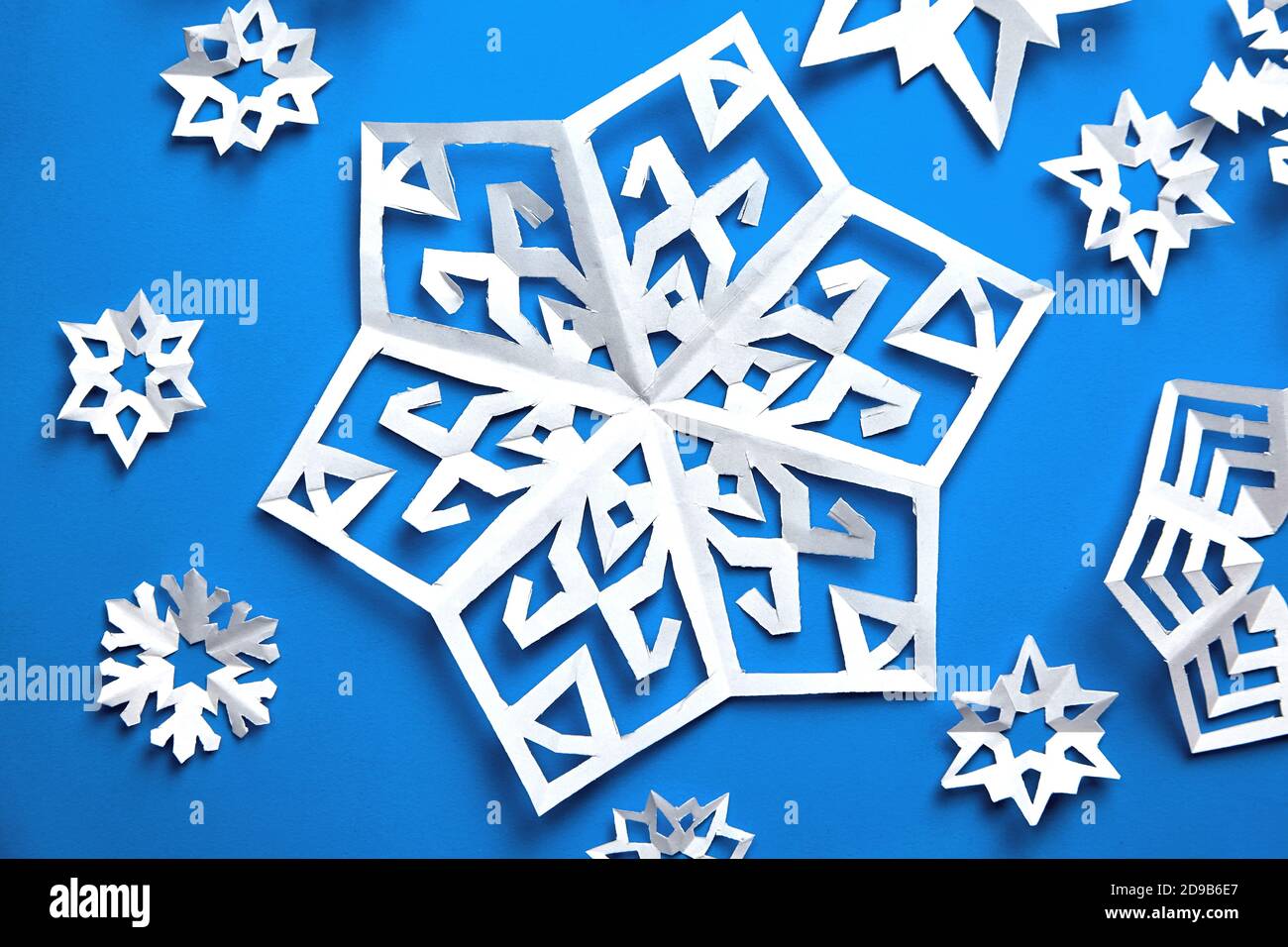 Handgemachte Papier Schneeflocken auf blauem Hintergrund Stockfoto