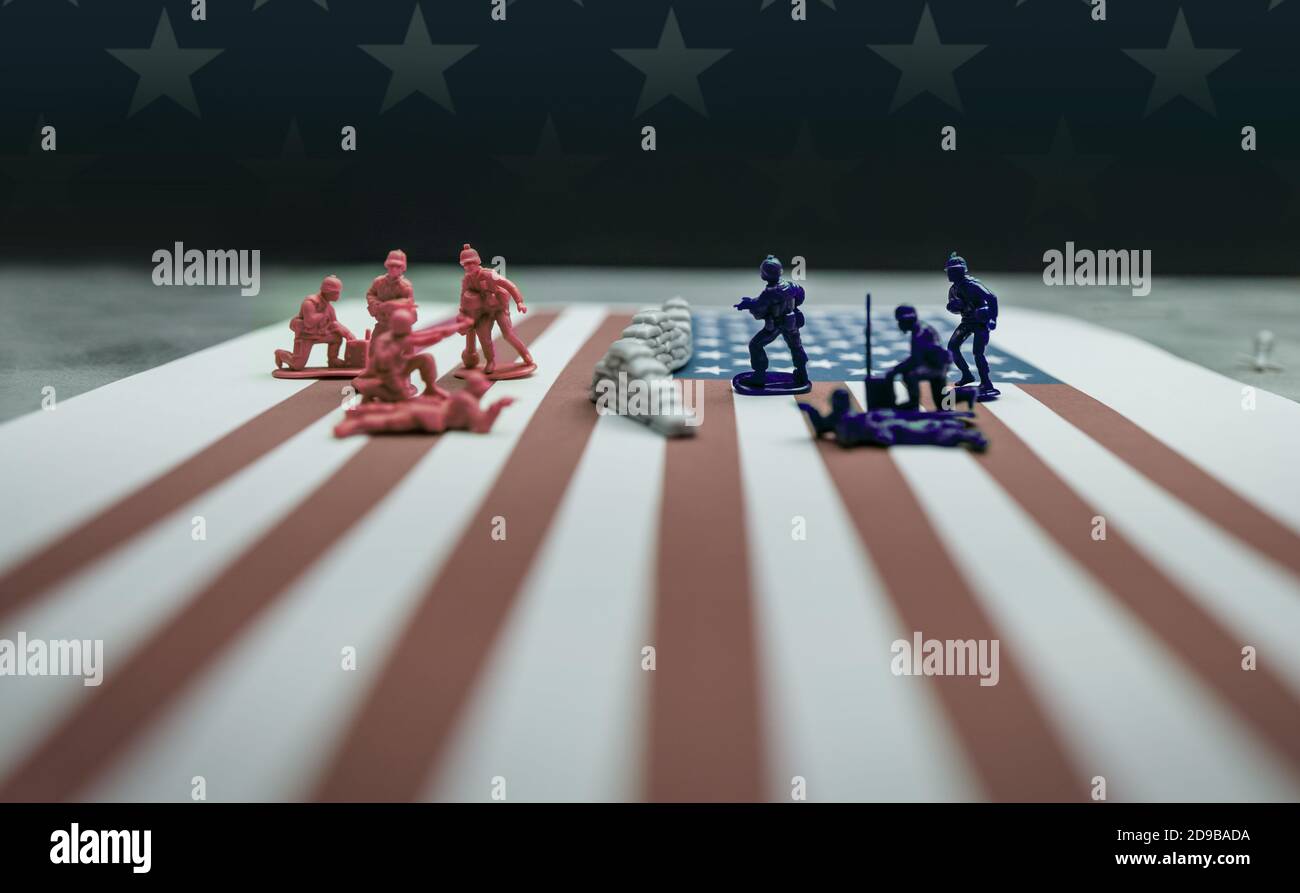 Miniatur-Soldaten von Angesicht zu Angesicht, eine Gruppe ist rot, die andere ist blau ... kämpfen auf der amerikanischen Flagge. Stockfoto