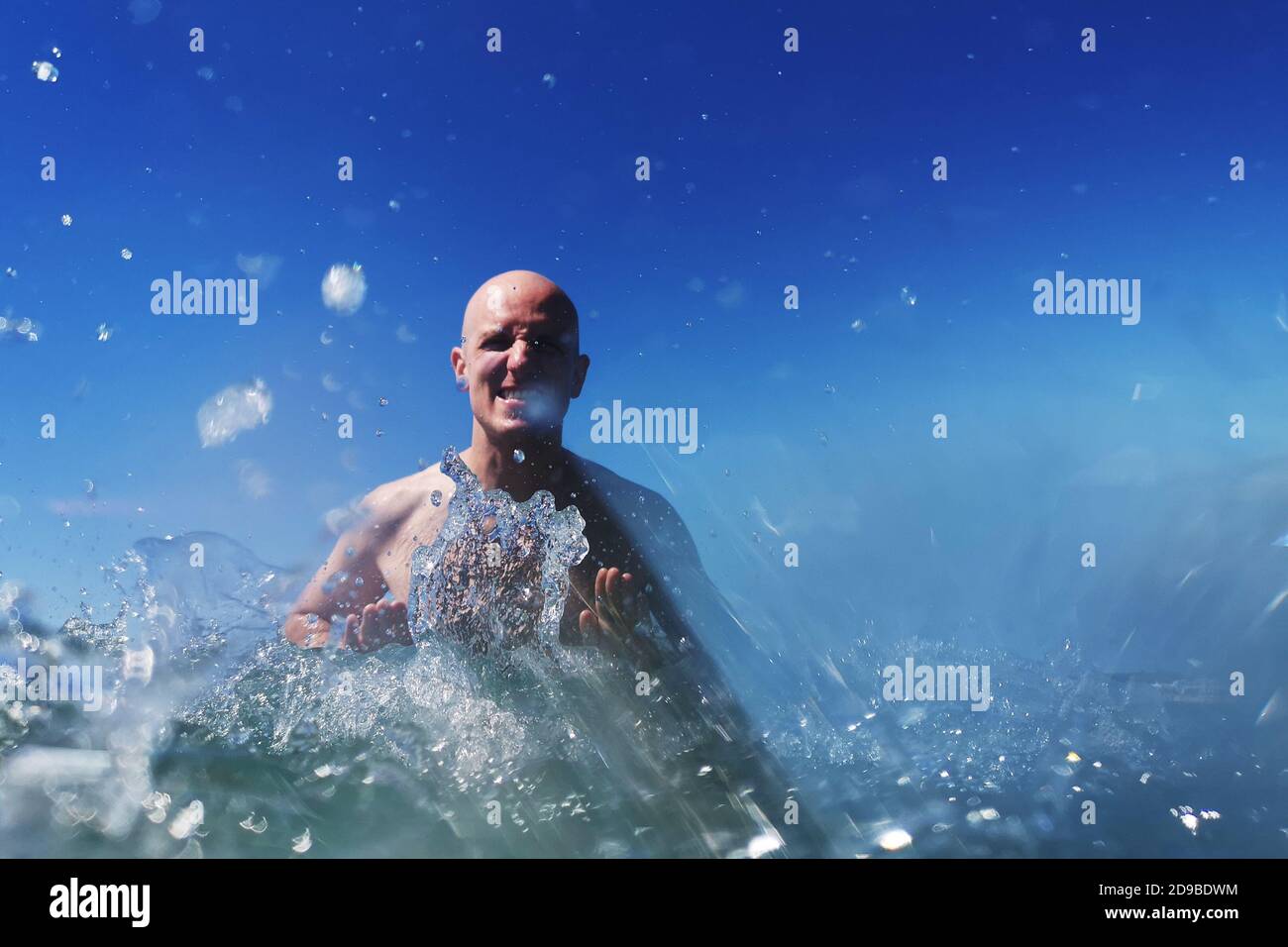 Mann, der im Meer steht und Wasser spritzt, Italien Stockfoto