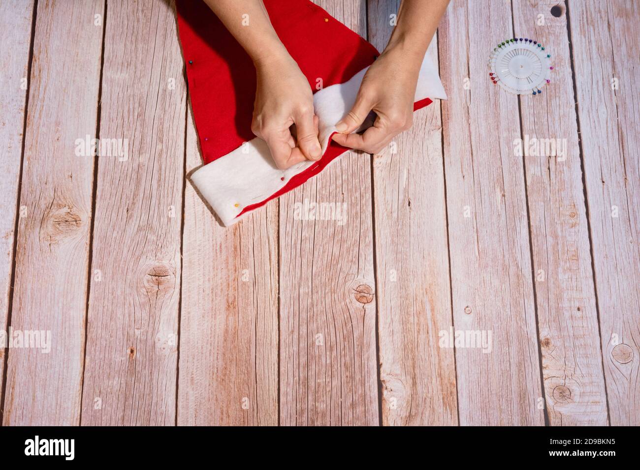 Master-Klasse auf die Schaffung eines roten Hut des Weihnachtsmannes. Befestigen Sie den weißen Teil mit den Händen mit Nähnadeln am Hut des Weihnachtsmannes. Schritt-für-Schritt-Anweisungen. St Stockfoto