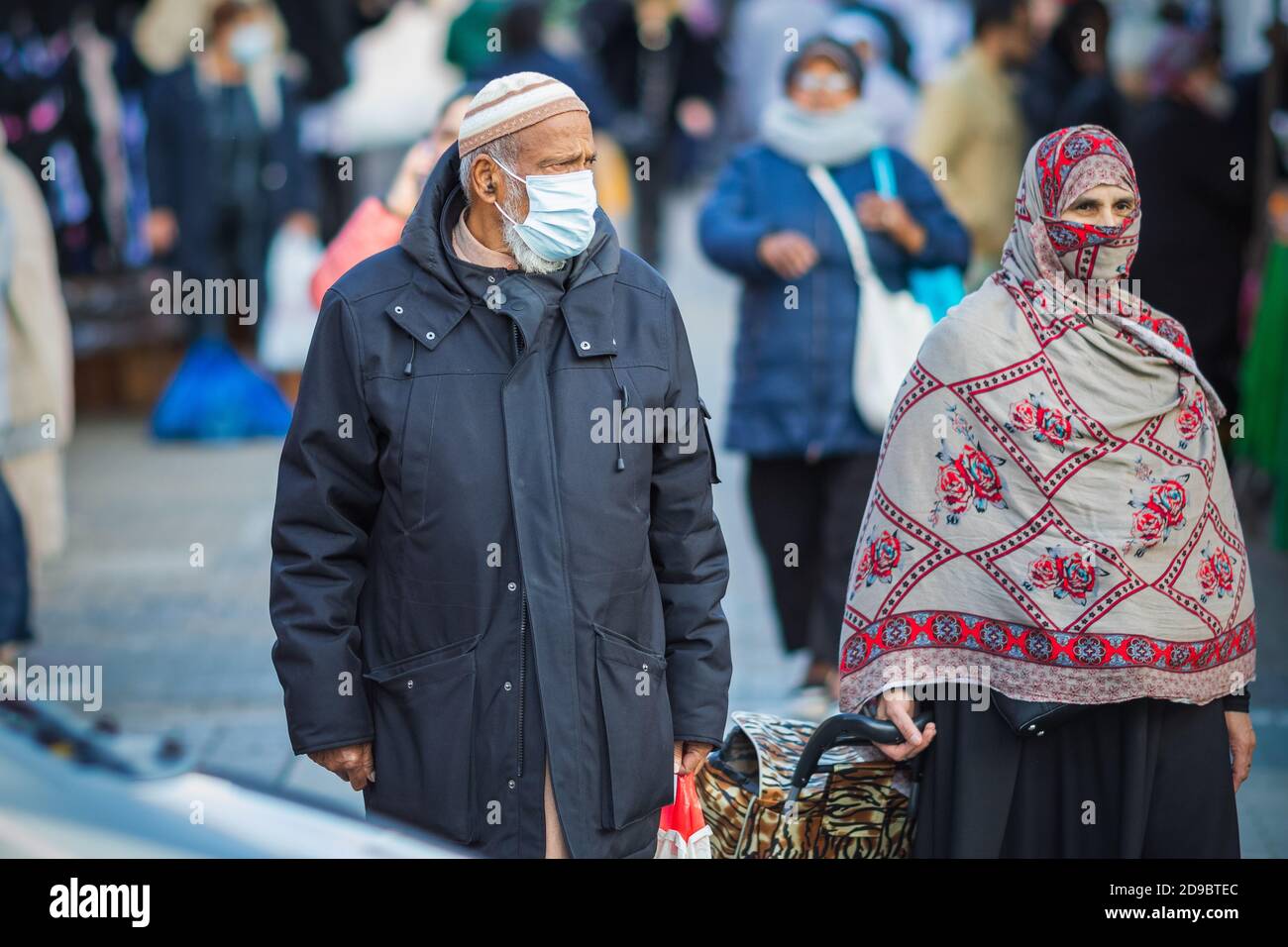 London, Großbritannien - 3. November 2020 - ein asiatischer muslimischer Mann und eine Frau, die eine Maske und einen Hijab als Gesichtsbedeckung tragen, während sie auf dem Walthamstow-Markt einkaufen Stockfoto