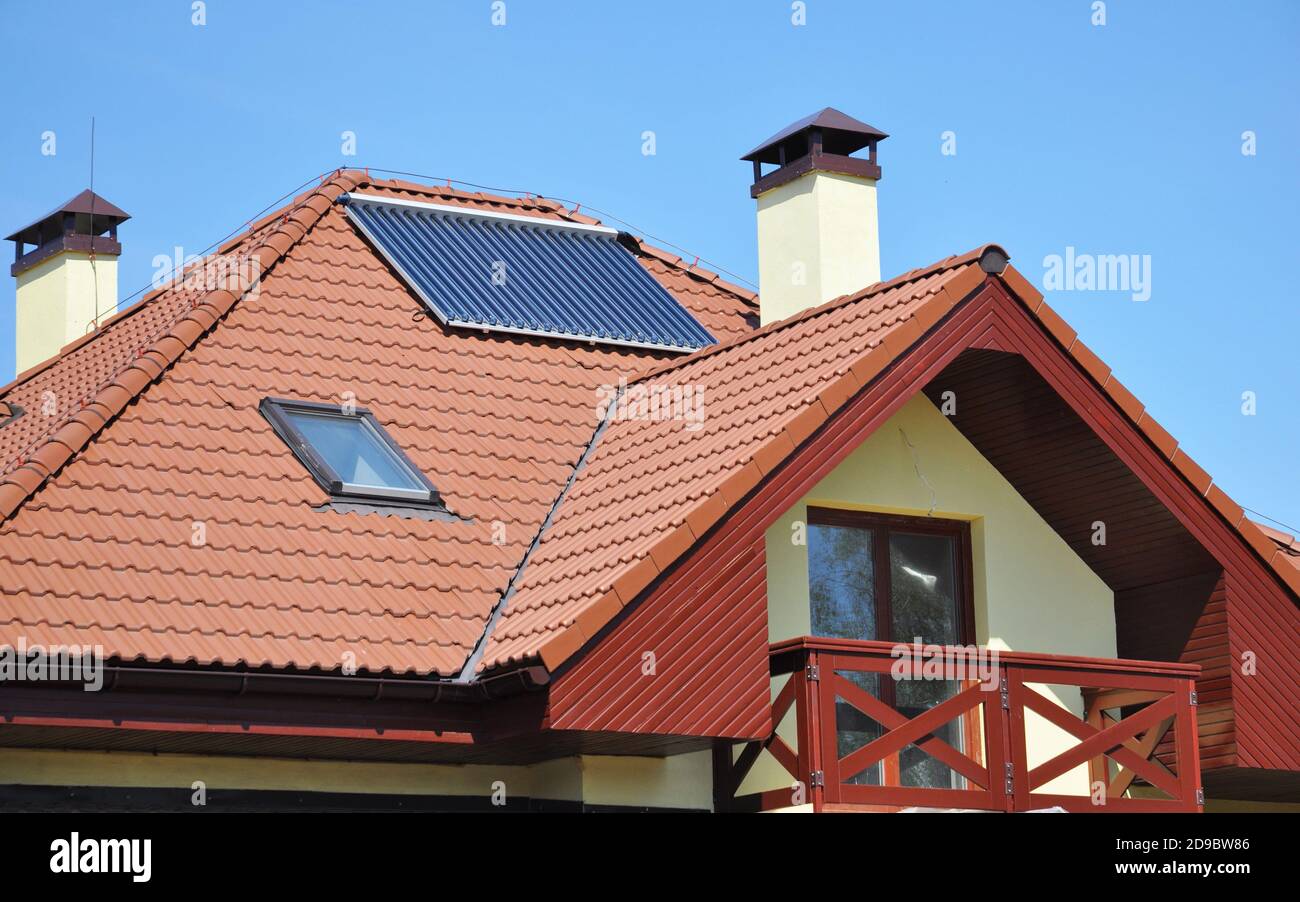 Ein modernes Haus mit Metall-Fliesendach, Dachfenster, Solarpaneel, Kamin, offenen Balkon und Fenster im Dachgeschoss. Stockfoto