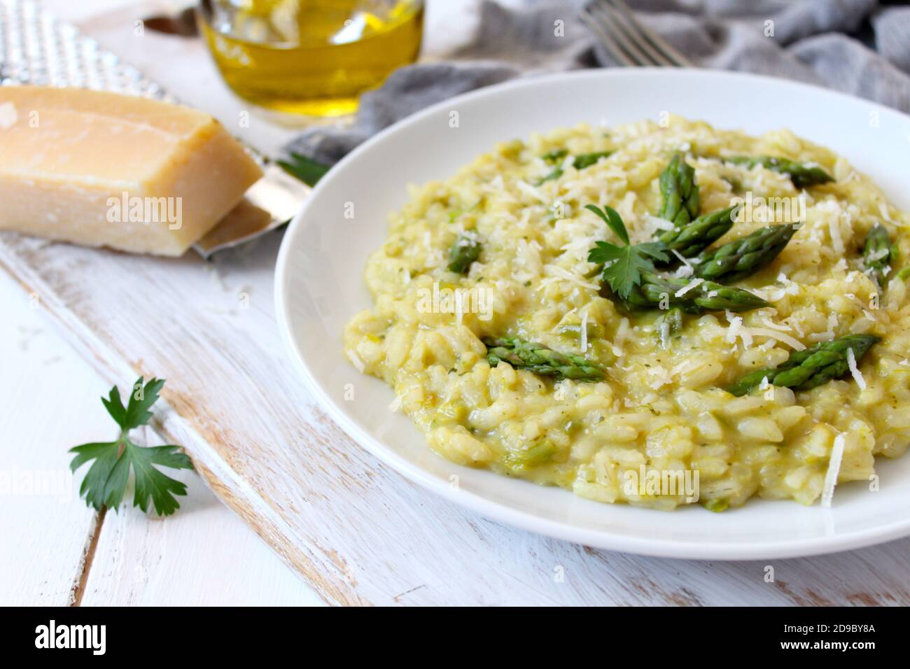 Italienisches Risotto mit Frühlingsspargel und Parmesankäse auf hellem Hintergrund. Draufsicht mit Kopierbereich. Stockfoto