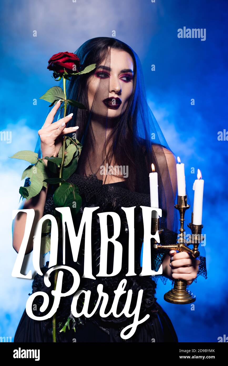Junge Frau in schwarzem Kleid und Schleier hält Rose und Brennende Kerzen nahe Zombie Party Schriftzug auf blau mit Rauch Stockfoto