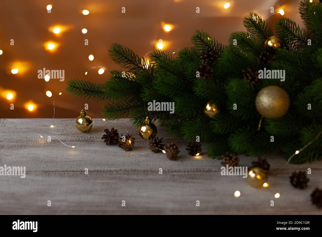 Weihnachtsbaum mit goldenen Kugeln auf einem Holztisch geschmückt In weißer Farbe im Schein von warmen hellen Girlanden Stockfoto