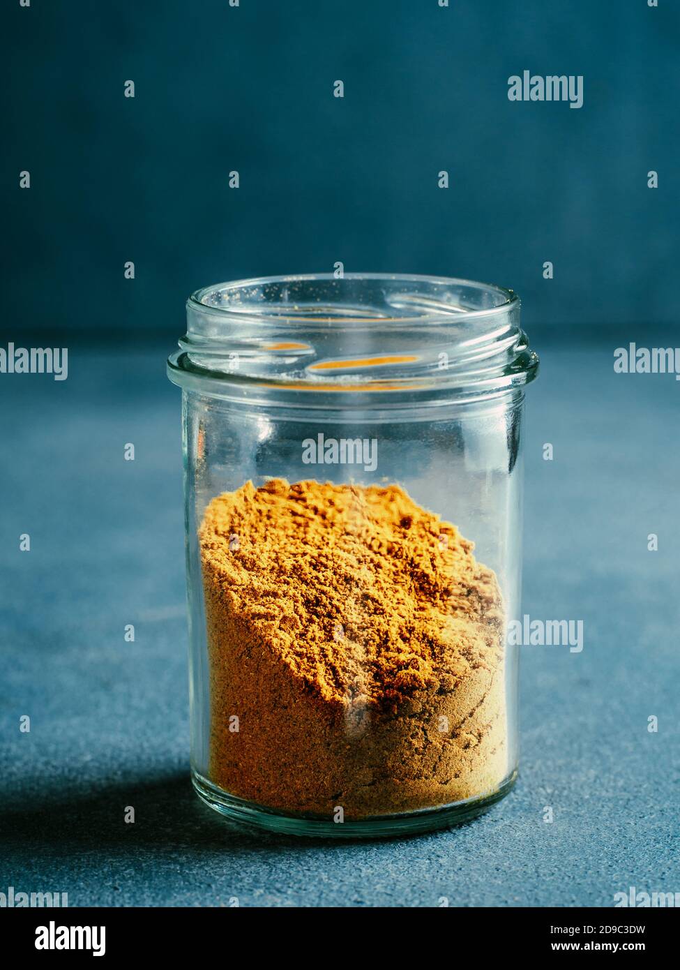 Indische oder pakistanische Masala Pulver in Glas. Hausgemachte trockene Curry Garam Masala Mischung Gewürze Mischung auf dunkelgrauem Hintergrund. Vertikal Stockfoto