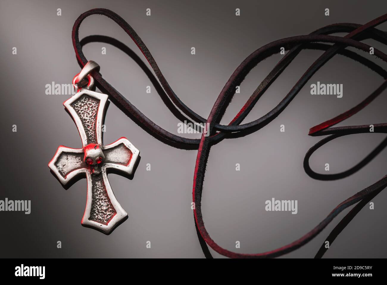 Metallic-Kreuz mit Lederspitze auf dunklem, gradienten Hintergrund Stockfoto