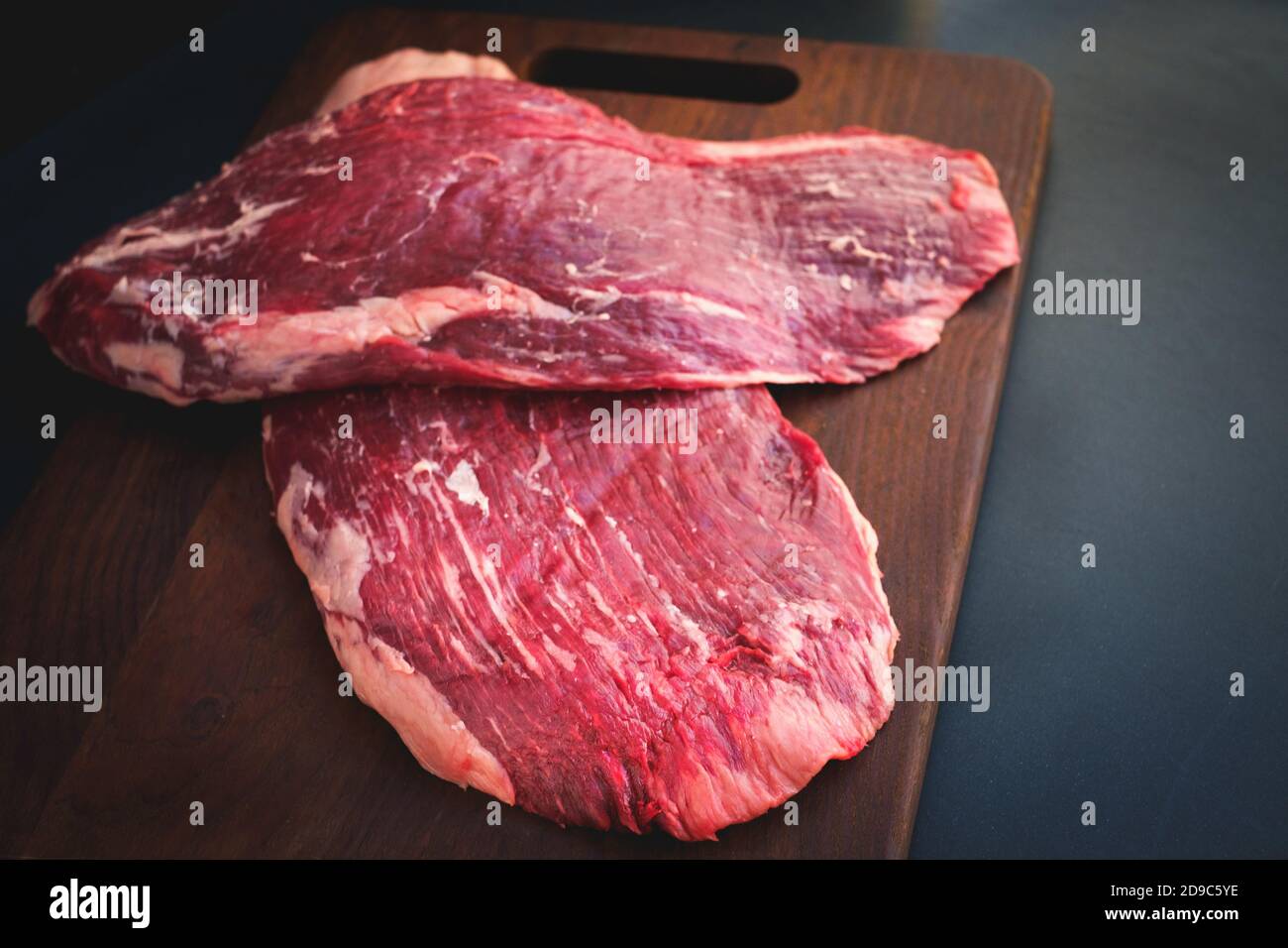 Zweiteiliges rohes Flankenrind auf einem Holzbrett auf Metzgerei, frisches Premium-Fleisch schwarzer angus auf dem Tisch Stockfoto