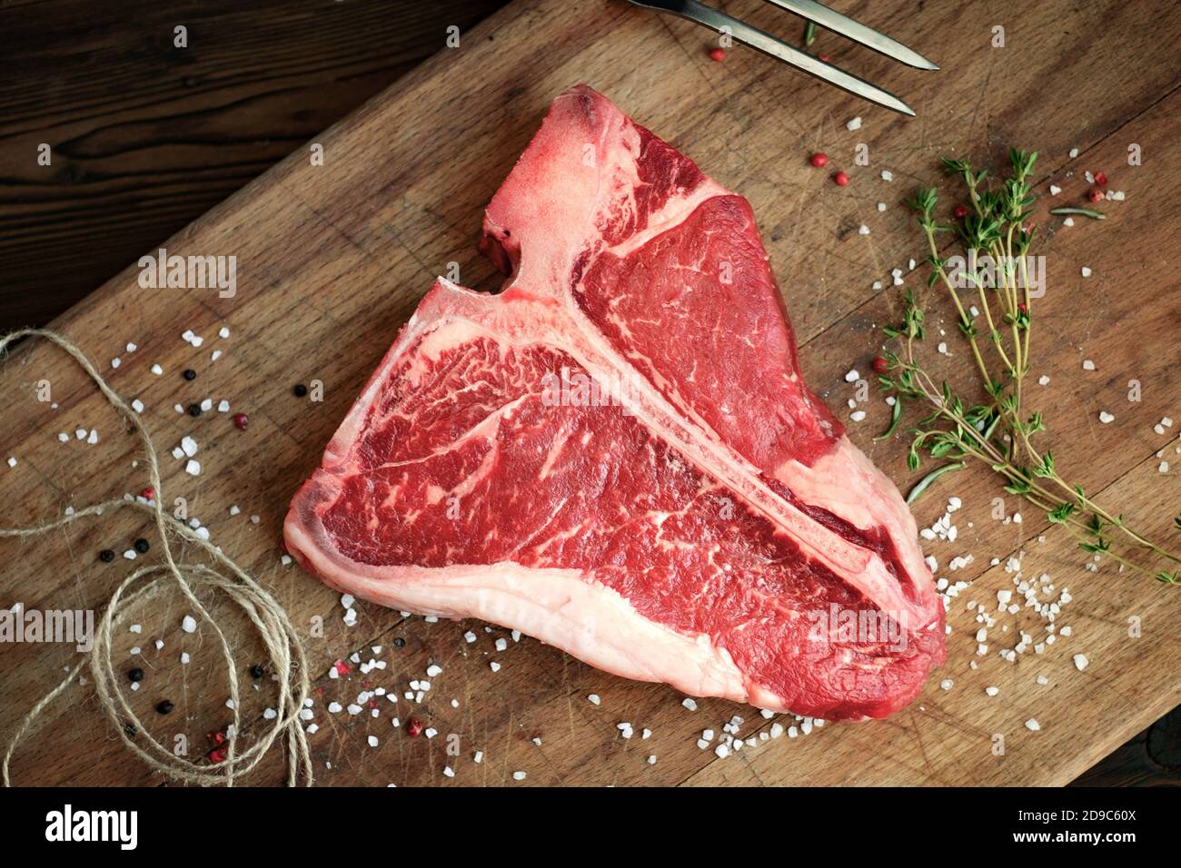 Rohes Rindersteak auf dem Fleischbrett mit Pfeffer, Salz, Kräutern, enger Garnierung, Draufsicht Stockfoto