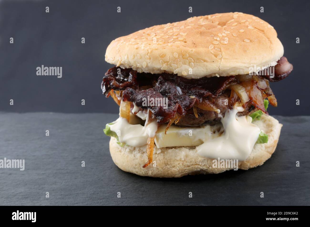 Hausgemachter Käse-Burger mit gebratener Zwiebel Avocado und Speck Stockfoto