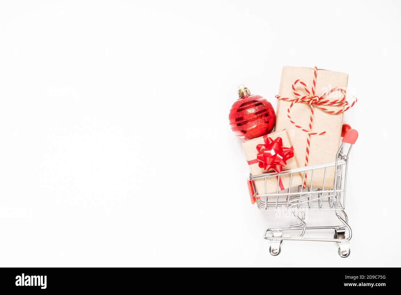 Warenkorb mit Geschenken und weihnachtskugel auf weißem Hintergrund mit Kopierplatz. Stockfoto
