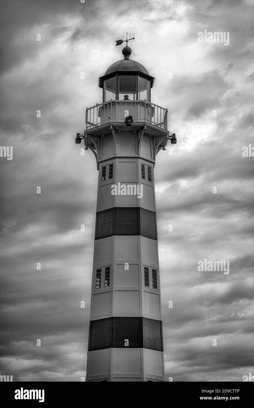 MALMÖ, SCHWEDEN - 21. AUGUST 2020: Der Leuchtturm an der Hafeneinfahrt vor einem atemberaubenden, dramatischen Wolkenhimmel. In Schwarzweiß bearbeitet Stockfoto