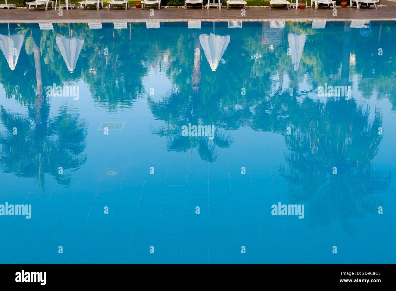Reflexionen von Palmen in der ruhigen blauen Wasser eines Schwimmbades konzeptionelle tropischen Sommerurlaub und Reisen Stockfoto