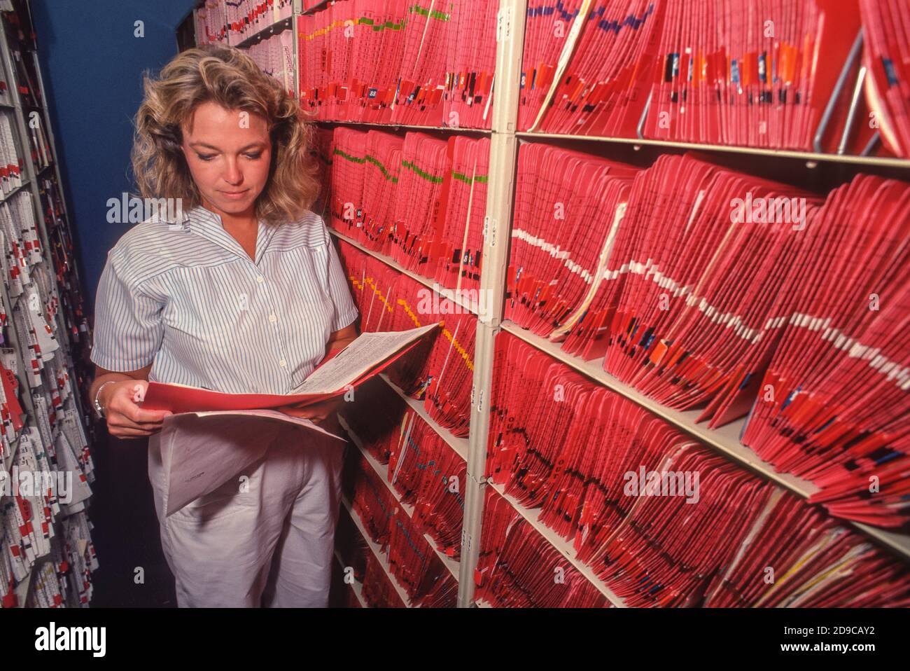 BURKE, VIRGINIA, USA, 5. SEPTEMBER 1991 - Frau Mitarbeiter überprüft medizinische Charts in der Ablage Bereich in der medizinischen Klinik. Stockfoto