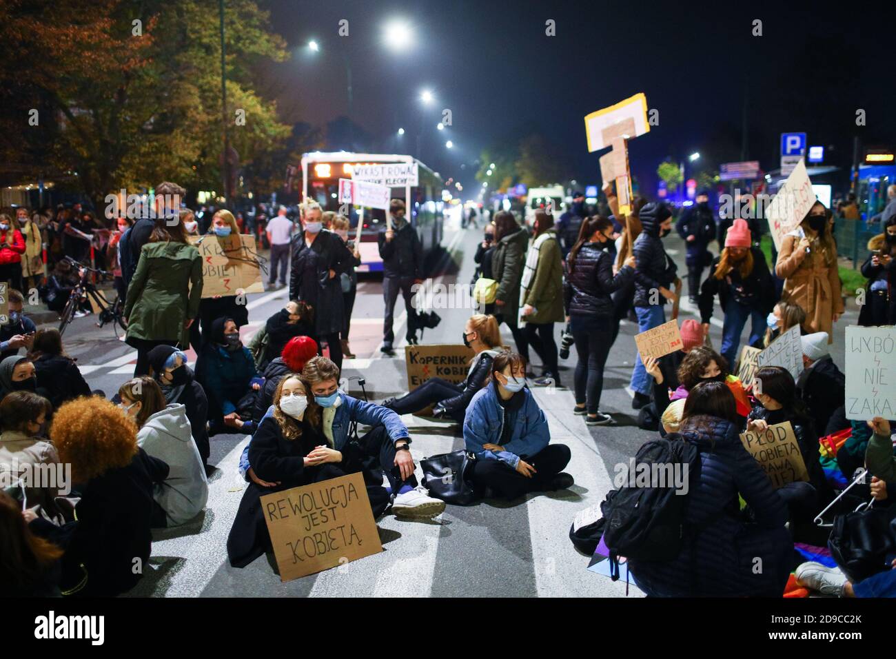 Ein Paar mit einem Plakat, auf dem "Revolution ist weiblich" steht, umarmt die Leute, die die Straße blockieren. Das polnische Verfassungsgericht in seinem neuen, po Stockfoto