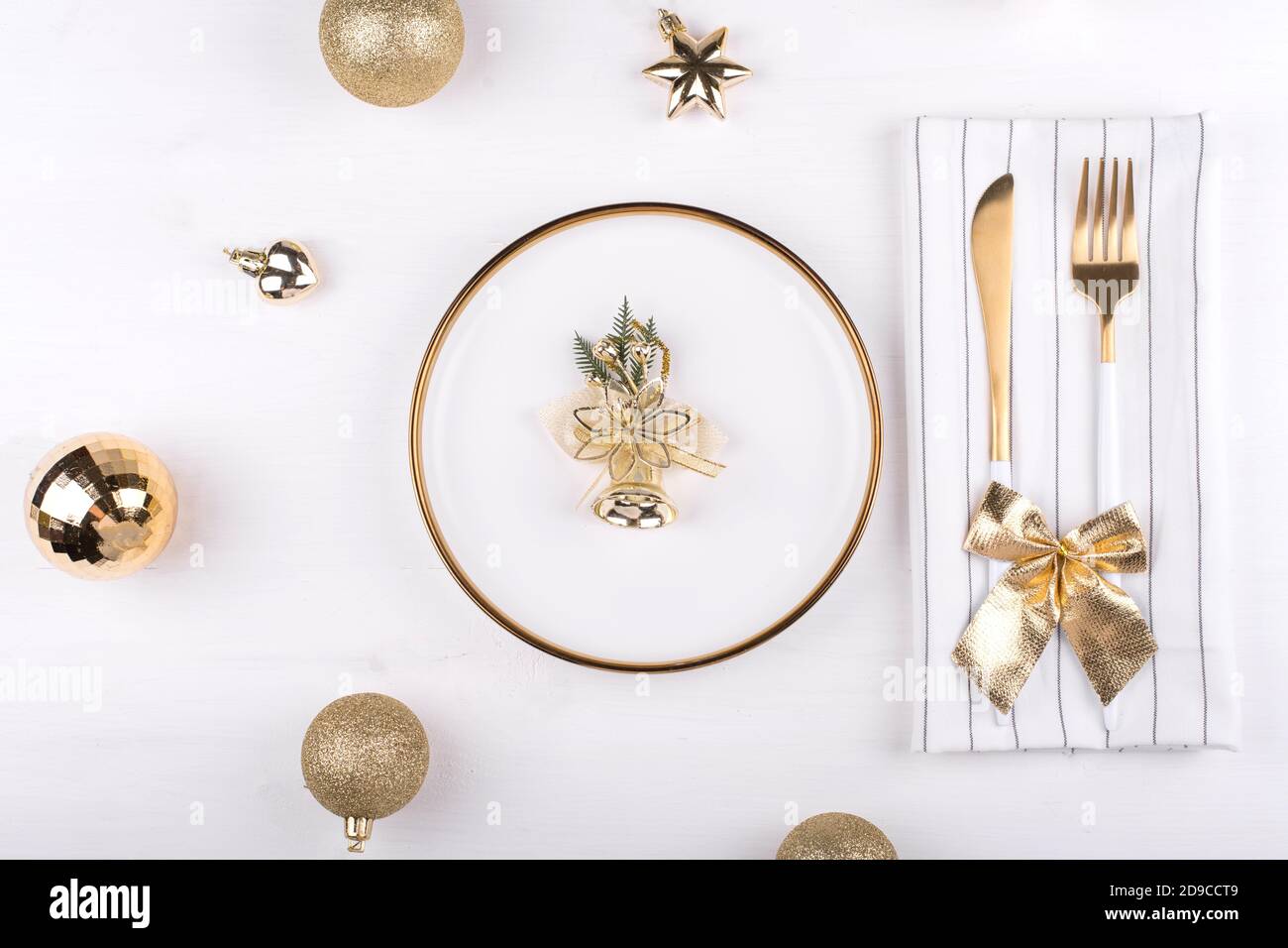 Weißer Teller mit goldenem Rand mit Weihnachtsschmuck, Neujahrsmenü, festliche Tischgestaltung Stockfoto