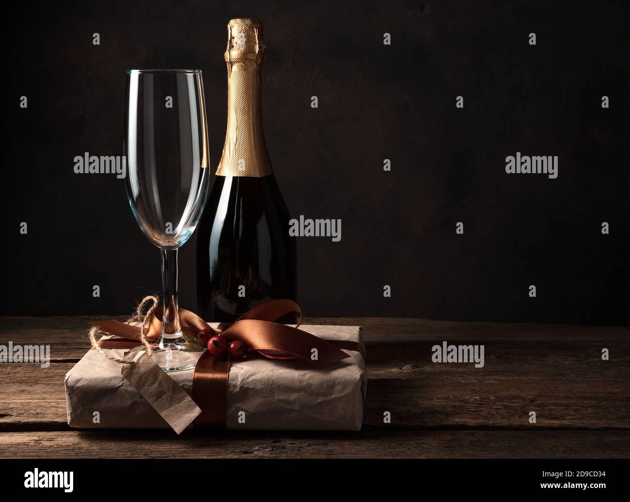 Geschenkbox, Champagner und Weinglas auf dunklem Holzhintergrund. Stockfoto