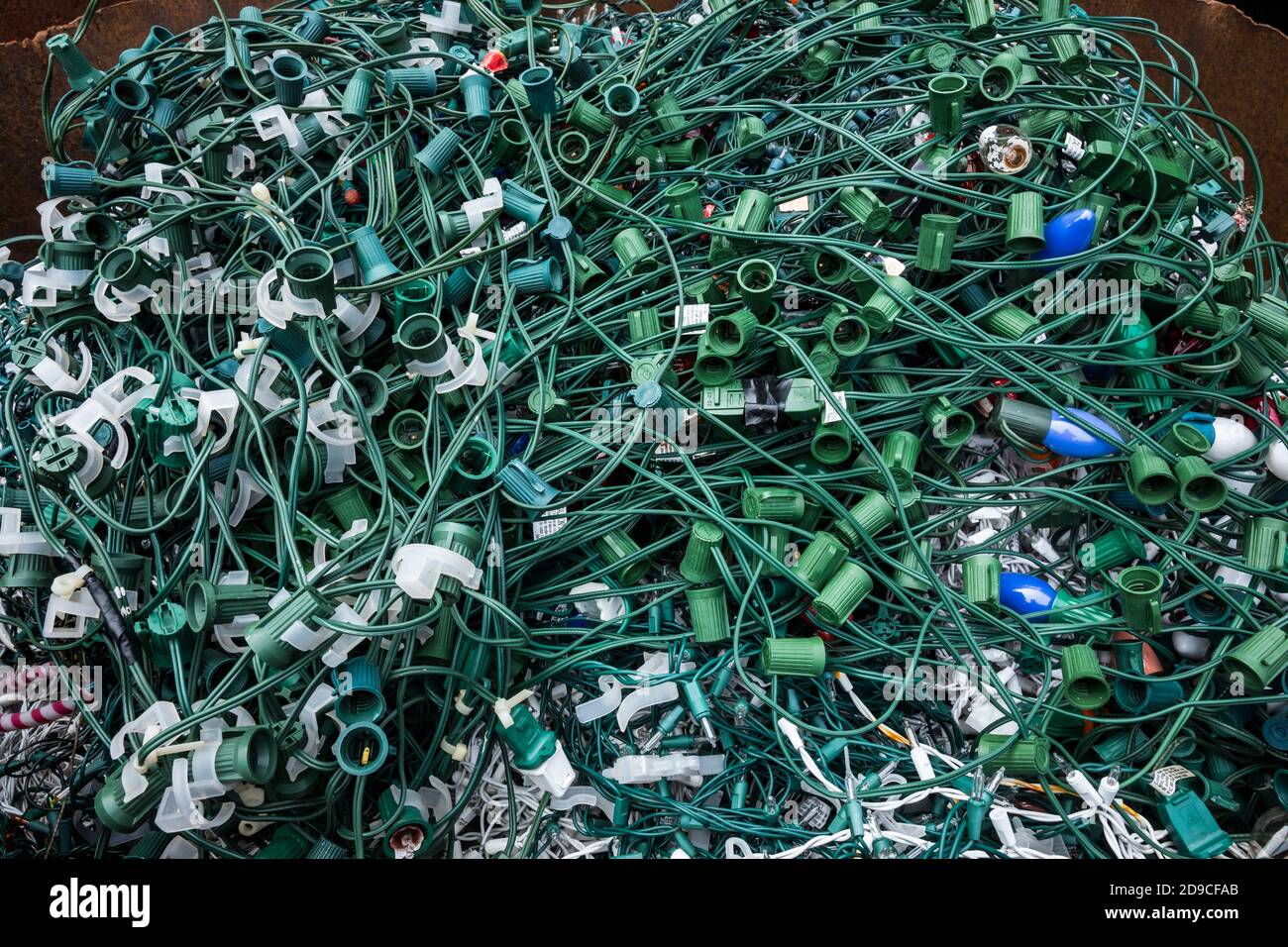 Dekorative Lichtdrähte für den Weihnachtsurlaub, die zum Recycling in einem Abfalleimer gestapelt sind. Stockfoto