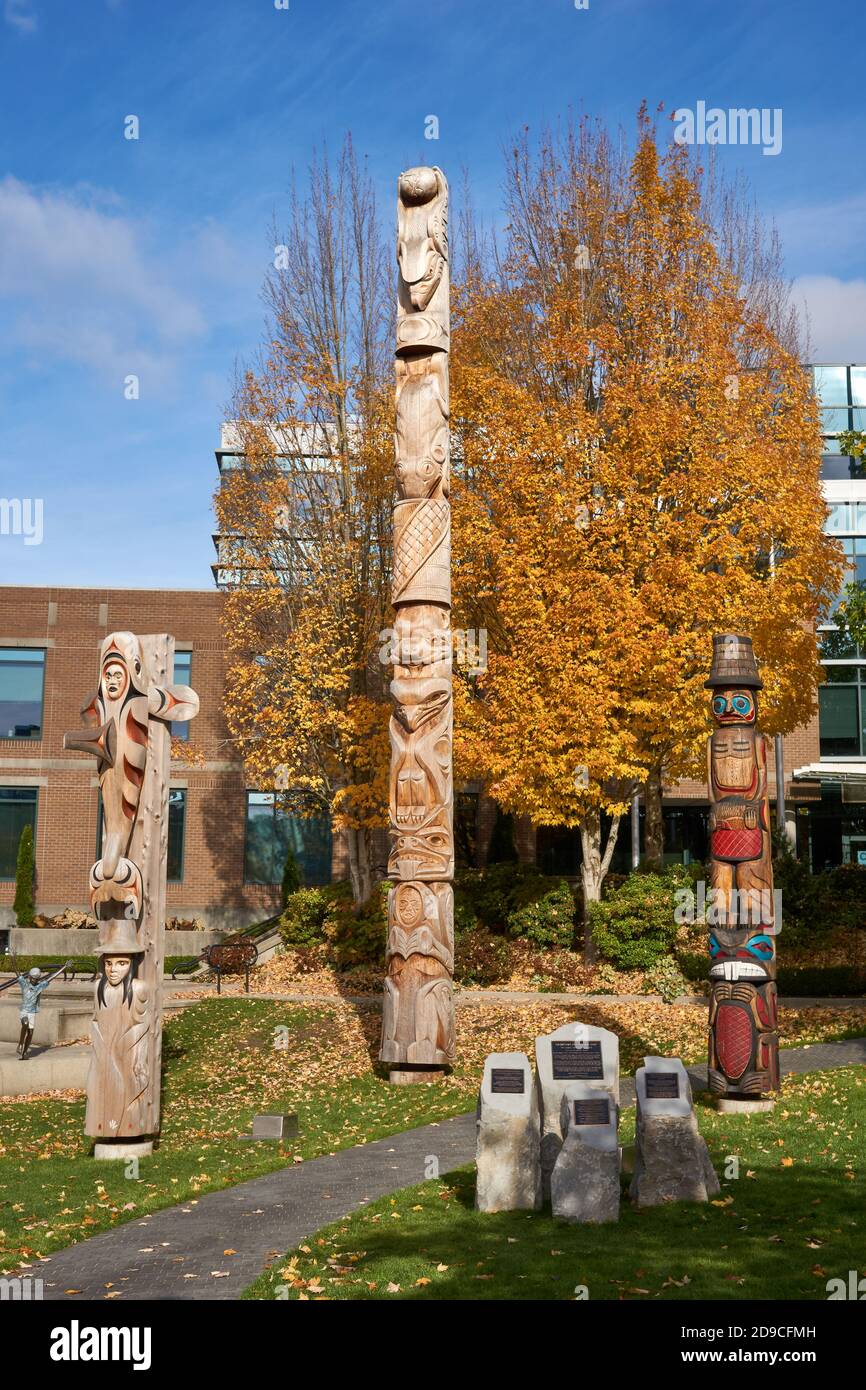 Kwakiutl style Versöhnung Totem Pol und Küste Salish Willkommen Beiträge außerhalb der Vancouver School Board Building, Vancouver, BC, Kanada Stockfoto