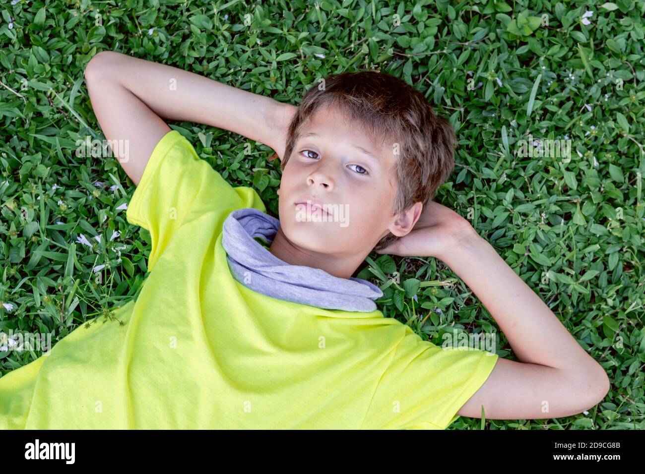 Niedlichen träumenden Jungen Teenager auf dem Gras liegen. Happy Childhood Konzept. Stockfoto