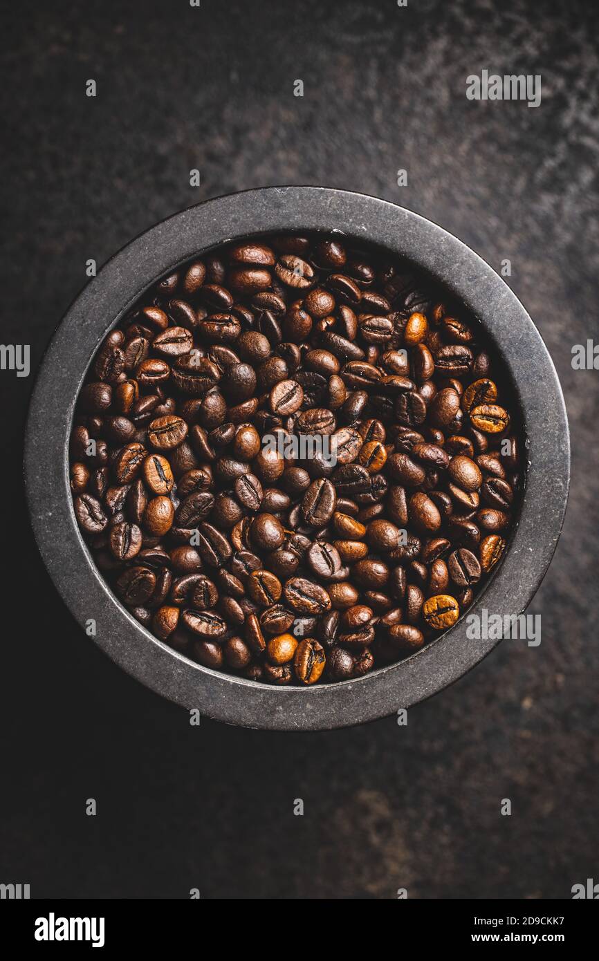 Geröstete Kaffeebohnen in Schüssel auf schwarzem Tisch. Draufsicht. Stockfoto