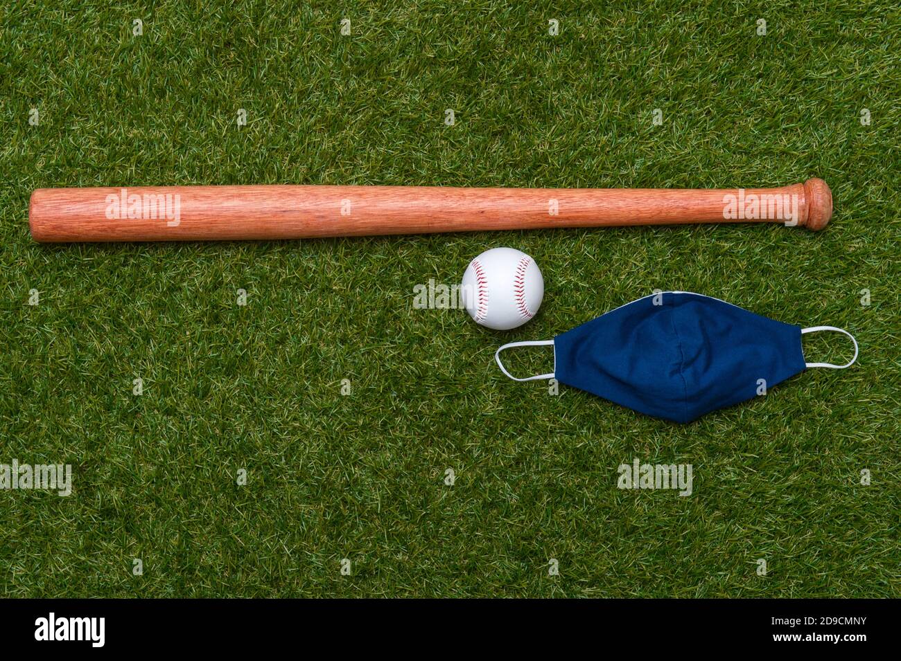 Baseballschläger, Ball und Maske isoliert auf einem Grasfeld. Baseball-Saison mit Gesichtsmaske. Sicheres Sportkonzept Stockfoto