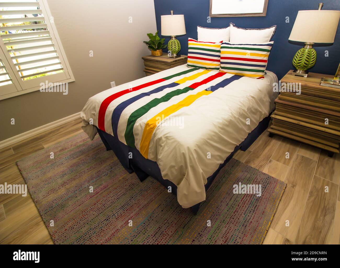 Schlafzimmer Mit Farbenfroher Bettdecke, Nachttischen Und Tischlampen Stockfoto