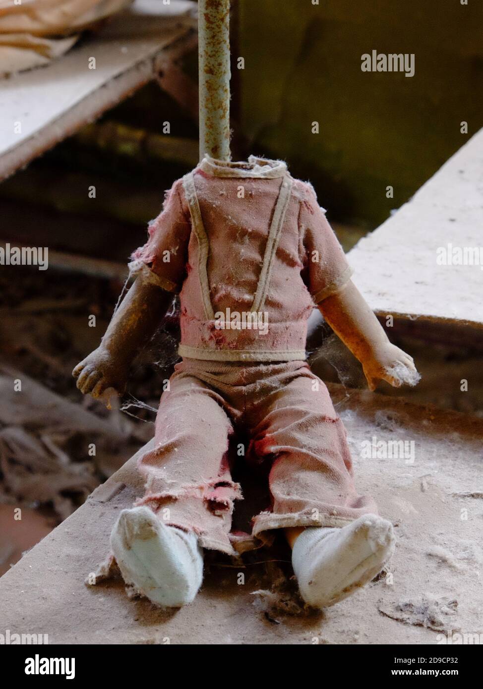 Kinderpuppe ohne Kopf. Ein schmutziges, zerbrochenes Kinderspielzeug aus einem strahlenverseuchten Kindergarten in Tschernobyl. Stockfoto
