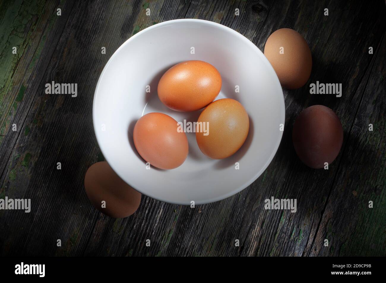 Nahaufnahme Foto von drei frischen Eiern in weißer Keramik Schüssel und drei andere auf Holz verfallenen Hintergrund Stockfoto