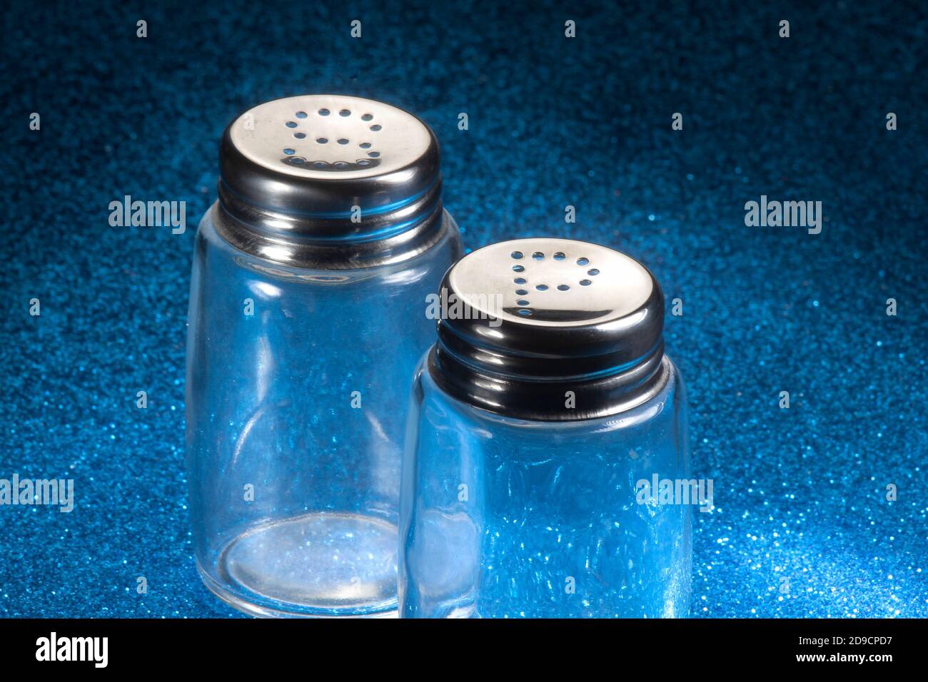 Leere Salz- und Pfefferstreuer leicht fleckig auf blauem Schminklicht Hintergrund Stockfoto