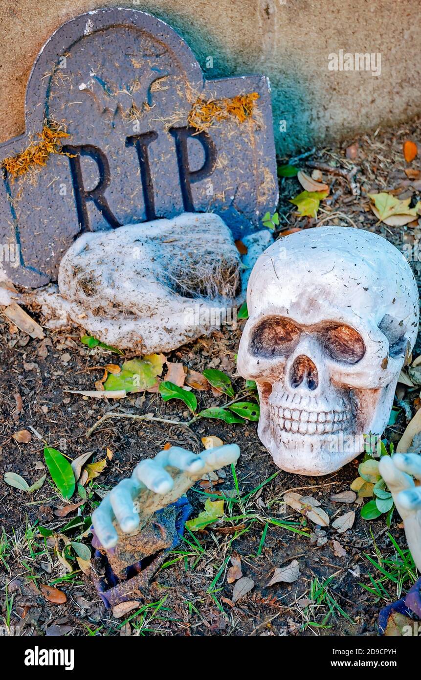 Ein gefälschter Grabstein, Totenkopf und geisterhafte Hände, die vom Boden reichen, sind Teil der Halloween-Dekorationen eines lokalen Unternehmens in Mobile, Alabama. Stockfoto