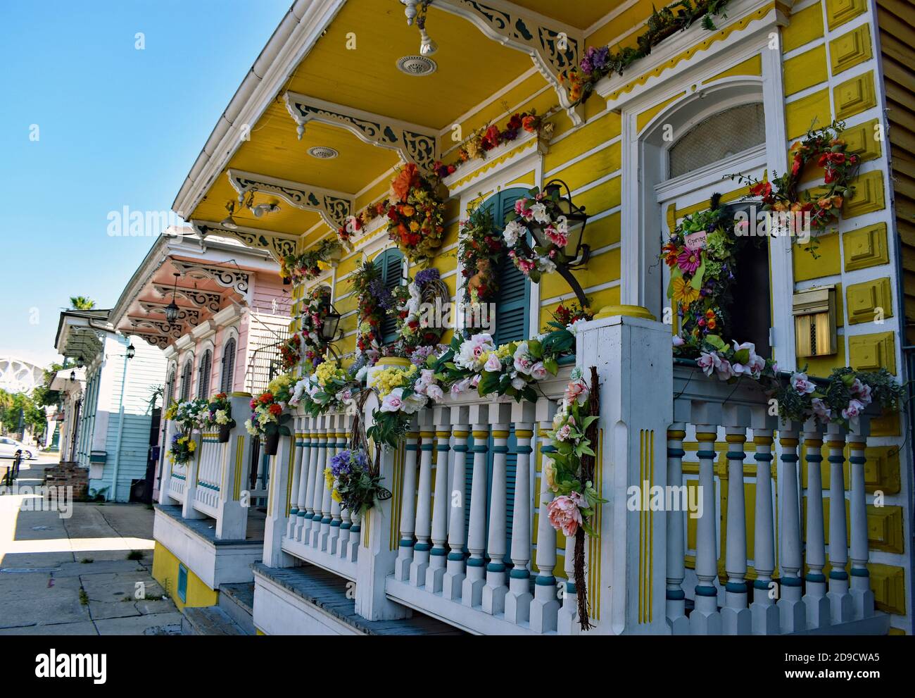 Ein traditionelles gelbes kreolisches Cottage in der St Ann Street im historischen French Quarter in New Orleans, Louisiana. Blumen schmücken die Veranda und Balustrade. Stockfoto