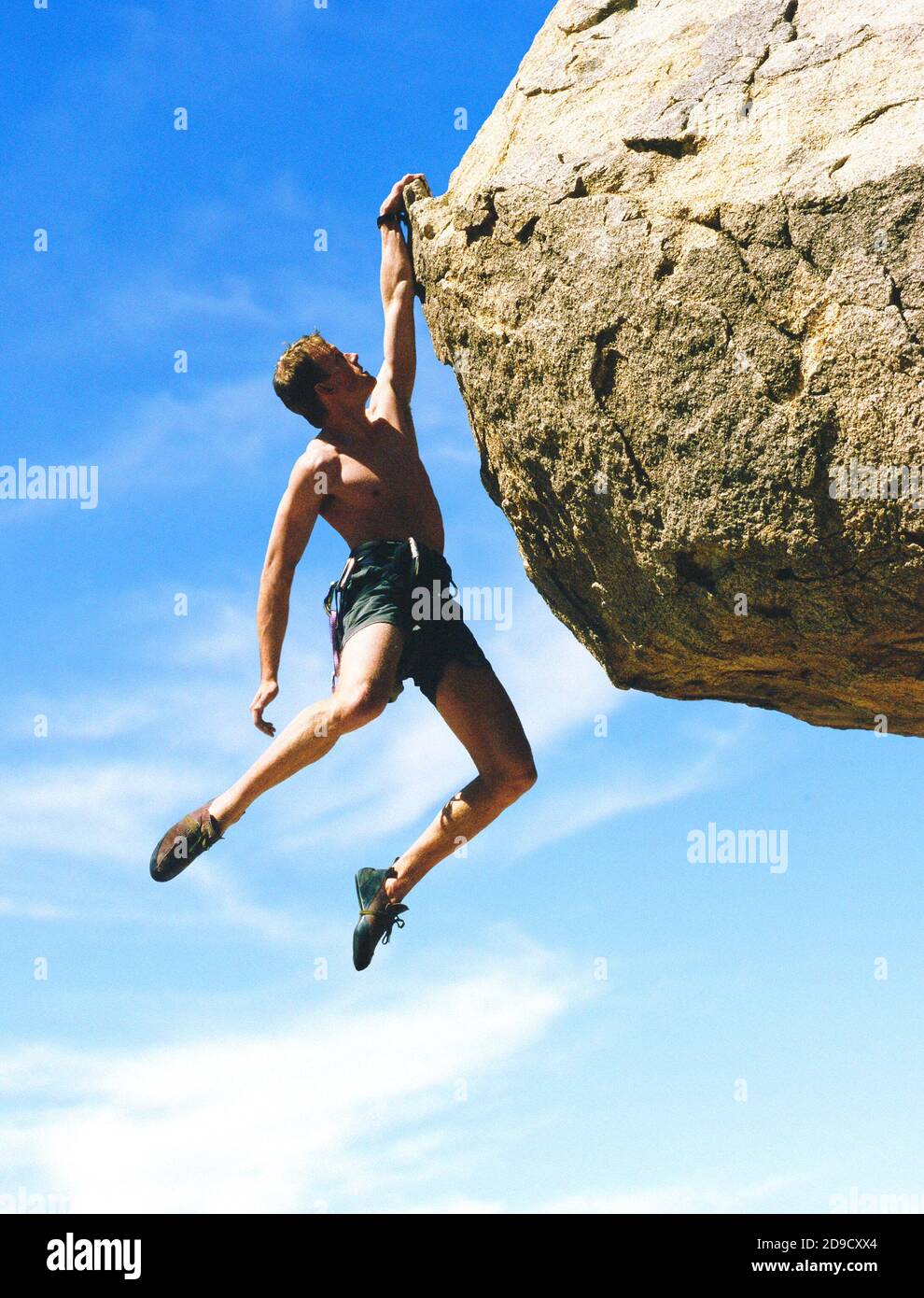 Ein Kletterer, der mit einer Hand an einem Felsen hängt. Stockfoto