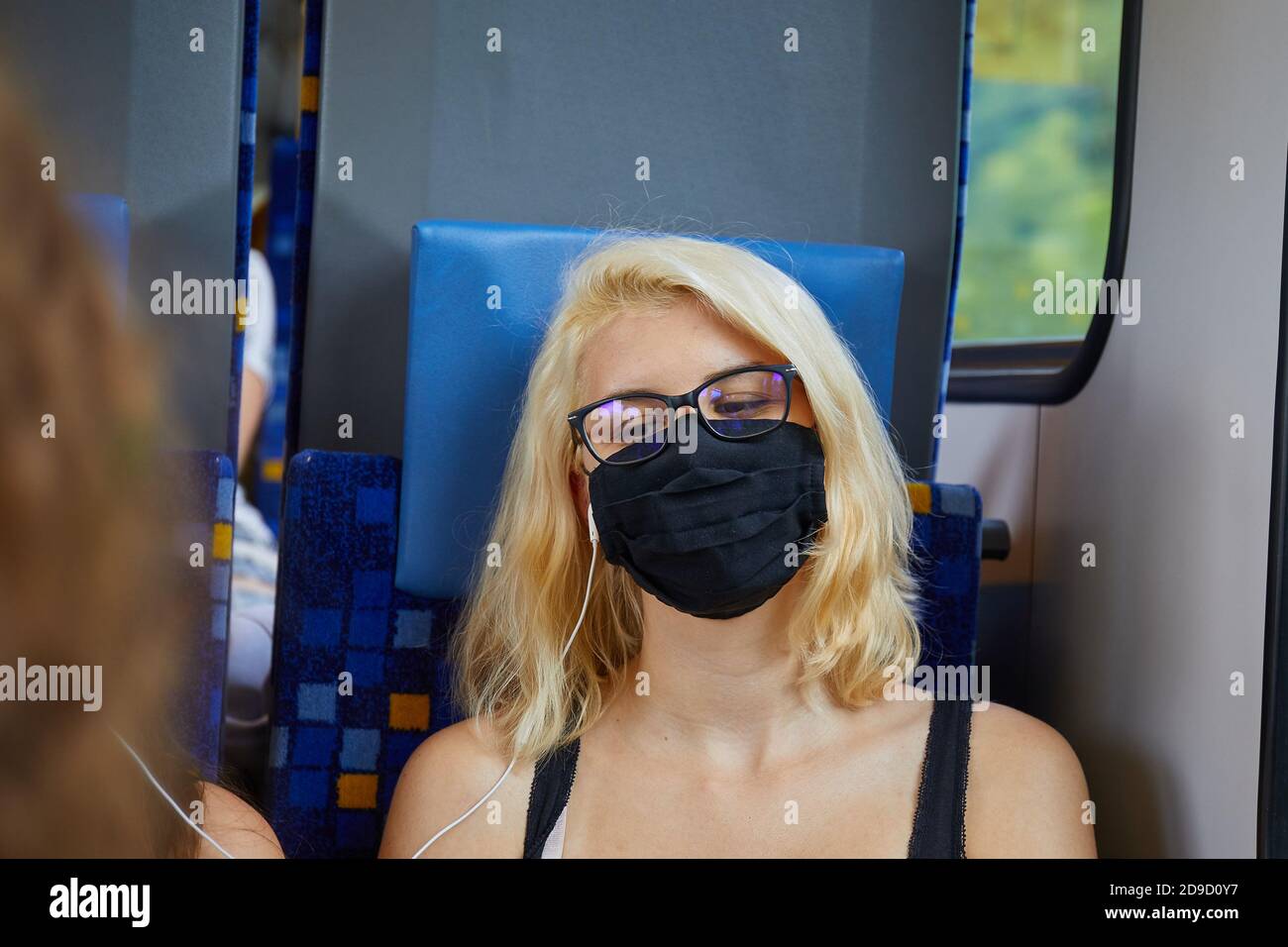 Junge Frau in einem Zug mit Maske Stockfoto