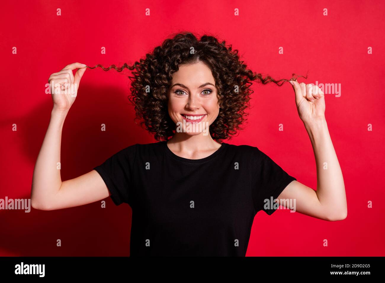 Nahaufnahme Porträt von schönen fröhlich wellig-haarige Mädchen berühren seidig glatt Haare isoliert über hellroten Hintergrund Stockfoto